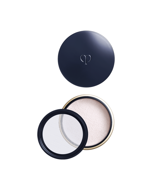 Photo of a round, blue-black and gold container with the lid on top, revealing the opened base and powder beneath. A transparent inner lid is placed on the left side. Shade: Light.