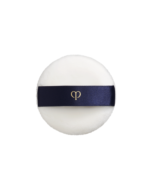 Photo of a soft, round and white "PUFF (TRANSLUCENT LOOSE POWDER)". It has a blue-black ribbon handle engraved with the gold brand-logo.