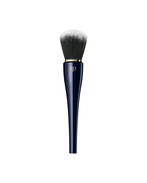 Photo of "POWDER BRUSH" with a  blue-black handle and a large, rounded bundle of bristles that spread softly. The bristles transition in color from black at the base to white at the tips.