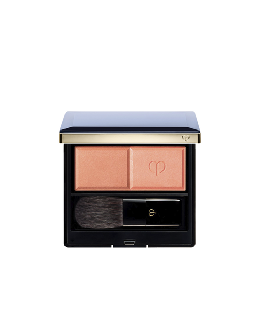 Photo of the "POWDER BLUSH DUO (REFILL)" set in a square compact with a navy lid and gold trim, containing two blush shades and a brush. The left side holds the matte powder, and the right side holds the pearly powder embossed with the logo.  Shade: 103.