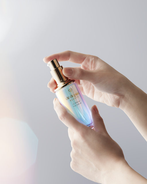 Photo of hands holding a bottle of "The Serum" by the gold pump.