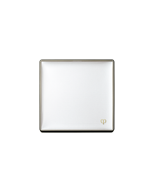 Photo of a case for "BRIGHTENING POWDER FOUNDATION". The lid of the white square compact is closed with the gold brand logo engraved on it on the bottom white corner.