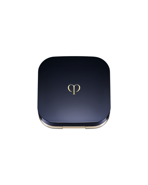 Photo of an exclusive case for "RADIANT CUSHION FOUNDATION DEWY" with the lid closed. It has a rounded square shape, with a blue-black lid featuring the brand logo in the center.