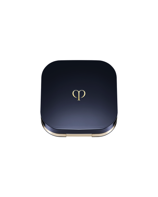 Photo of an exclusive case for "RADIANT CUSHION FOUNDATION NATURAL (REFILL)" with the lid closed. It has a rounded square shape, with a blue-black lid featuring the brand logo in the center.