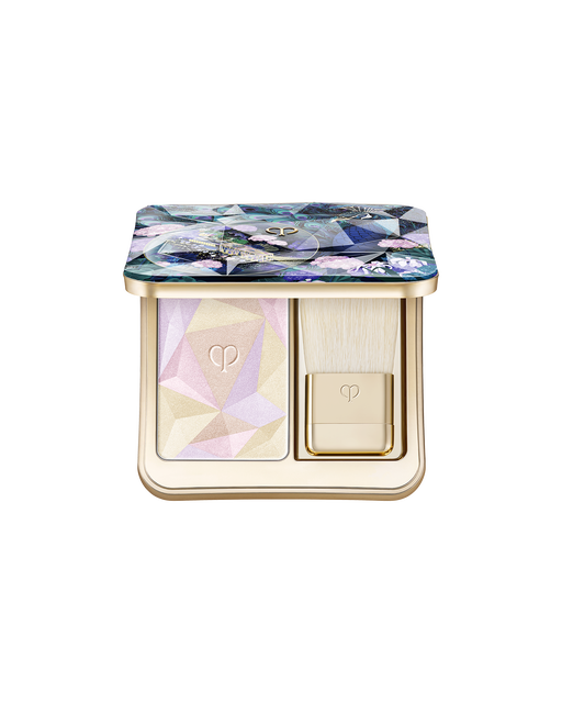Photo of the limited-edition THE LUMINIZING FACE ENHANCER, a highlighting powder with geometric patterns in blue, lavender, and green paired with a gold brush. The lid features a special design adorned with peacocks and floral motifs. Shade: Radiant Peafowl.