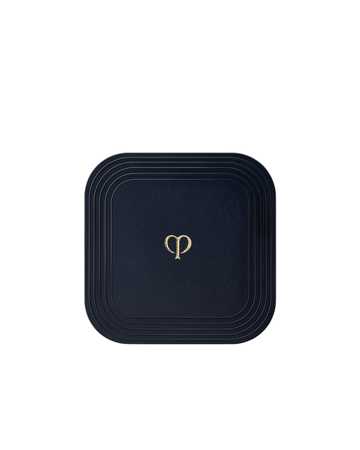 Photo of a square puff for "REFINING PRESSED POWDER", wrapped in smooth blue-black fabric.