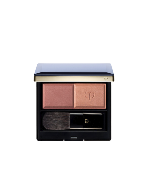 Photo of the "POWDER BLUSH DUO (REFILL)" set in a square compact with a navy lid and gold trim, containing two blush shades and a brush. The left side holds the matte powder, and the right side holds the pearly powder embossed with the logo.Shade: 105