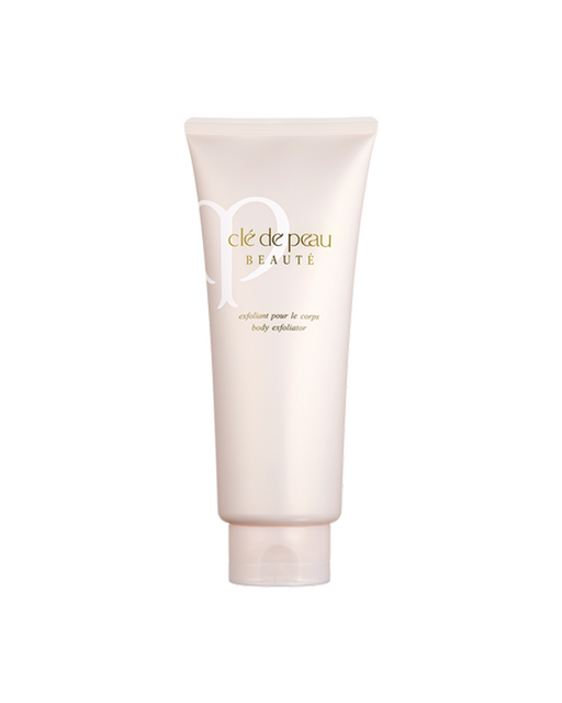 Photo of "BODY EXFOLIATOR" in a soft beige-pink tube with a subtle sheen. The gold brand logo and product name are printed on the front.