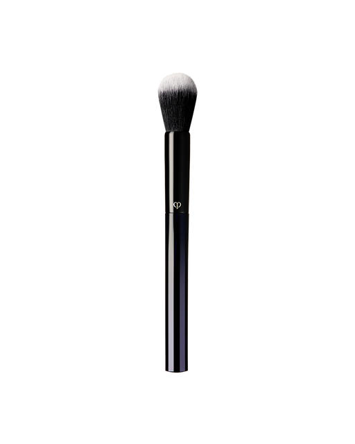 Photo of “BRUSH (FOR POWDER AND CREAM BLUSH)” featuring a sleek blue-black handle adorned with a gold brand logo, and topped with a rounded brush tip.