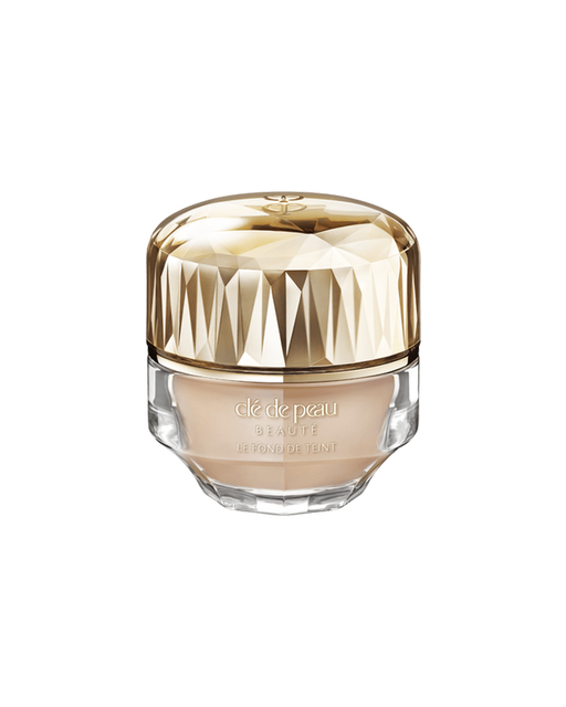 Photo of a jar of “THE FOUNDATION,” featuring an impressive multi-faceted gold cap and a substantial, luxurious glass bottle. SHADE: O20