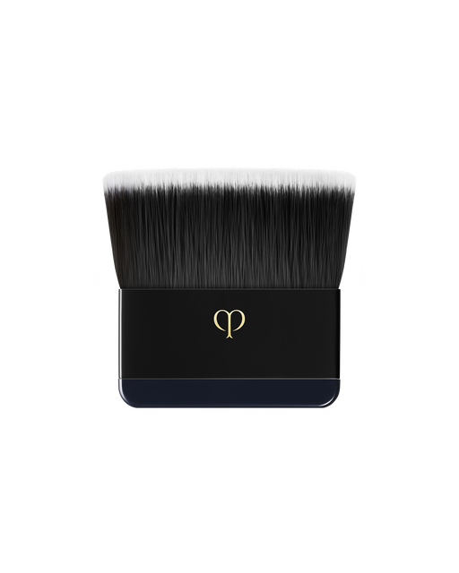 Photo of a flat brush designed specifically for "RADIANT POWDER FOUNDATION". The handle is engraved with the brand logo in gold.