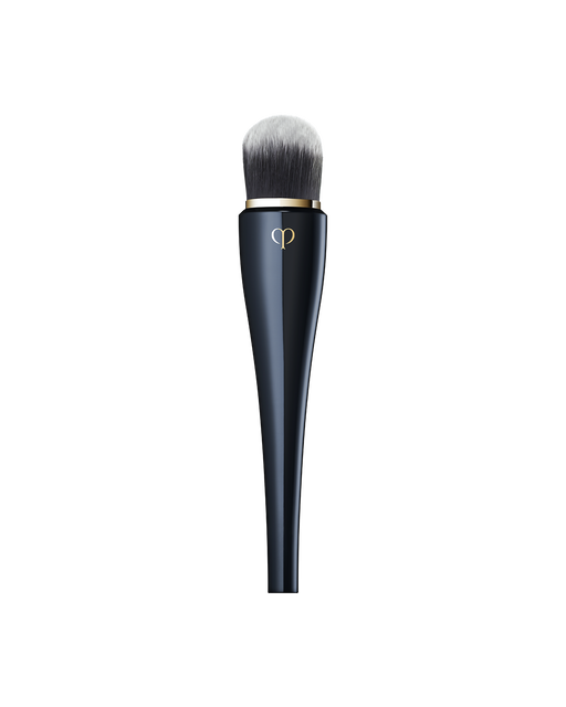 Photo of “LIGHT COVERAGE FOUNDATION BRUSH” featuring a sleek, blue-black handle with a gold brand logo, and soft, rounded bristles at the top designed for applying foundation.