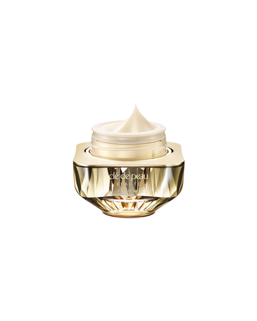 Photo of Clé de Peau Beauté’s high-performance cream “La Crème,” housed in a jewel-cut, translucent gold container. The lid is open, revealing the smooth cream inside.