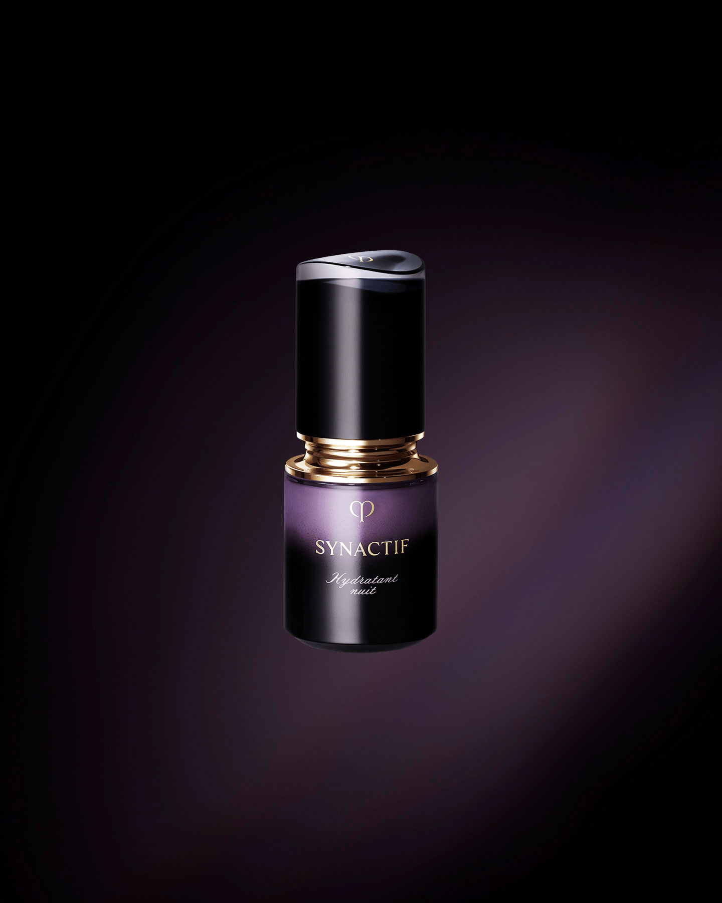 Photo of the Clé de Peau Beauté SYNACTIF NIGHTTIME MOISTURIZER. It is presented in a compact cylindrical bottle with a black-to-purple gradient. There is a gold accent between the cap and the body, and the 'SYNACTIF' logo is elegantly displayed on the front.