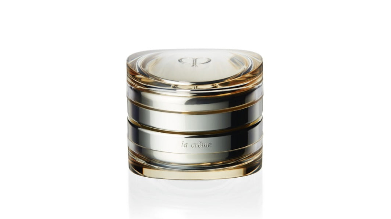 Photo of a luxurious glass container with a layered design of gold and silver tones. The front is engraved with the text “la crème,” and the brand logo is embossed on the top (former packaging).