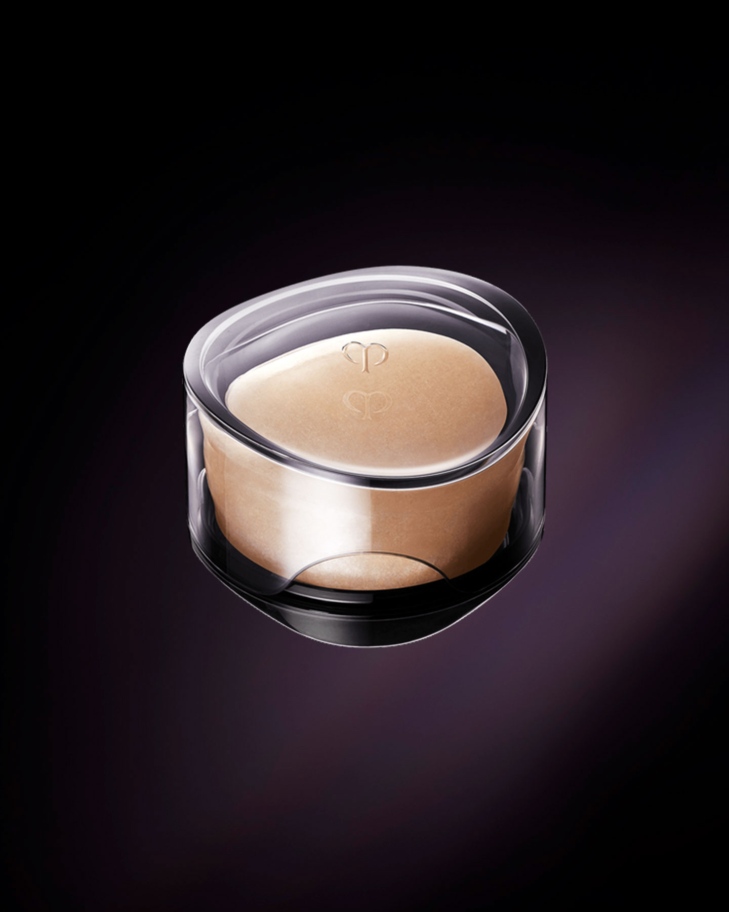 Photo of the luxurious Clé de Peau Beauté SYNACTIF SOAP. An elegant, round purifying soap in a warm peach hue is presented within a sophisticated, clear case. The brand's logo is delicately embossed on the surface of the soap and on the lid of its case.