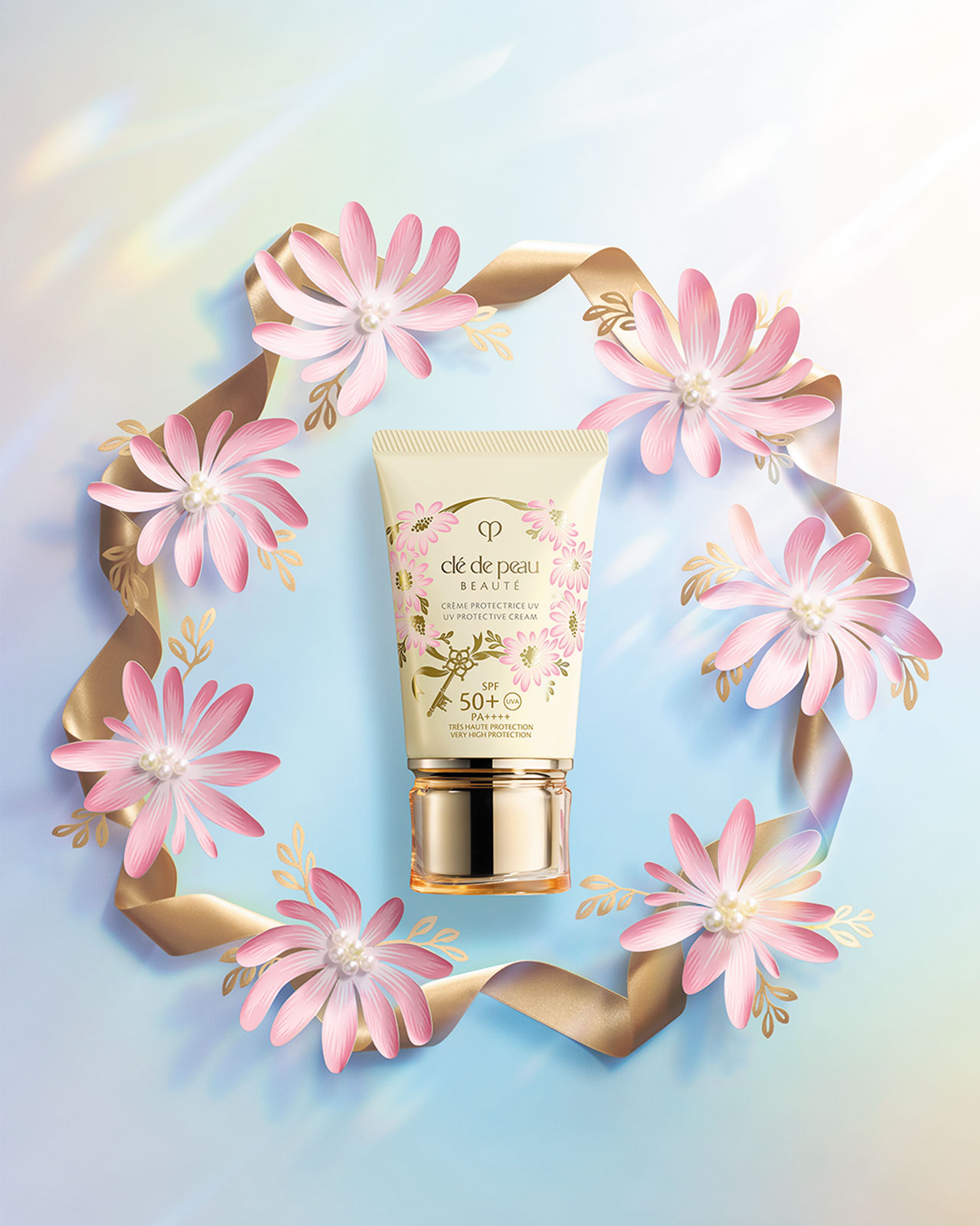 Photo of a UV PROTECTIVE CREAM with a gold cap, surrounded by pink flowers and a gold ribbon.