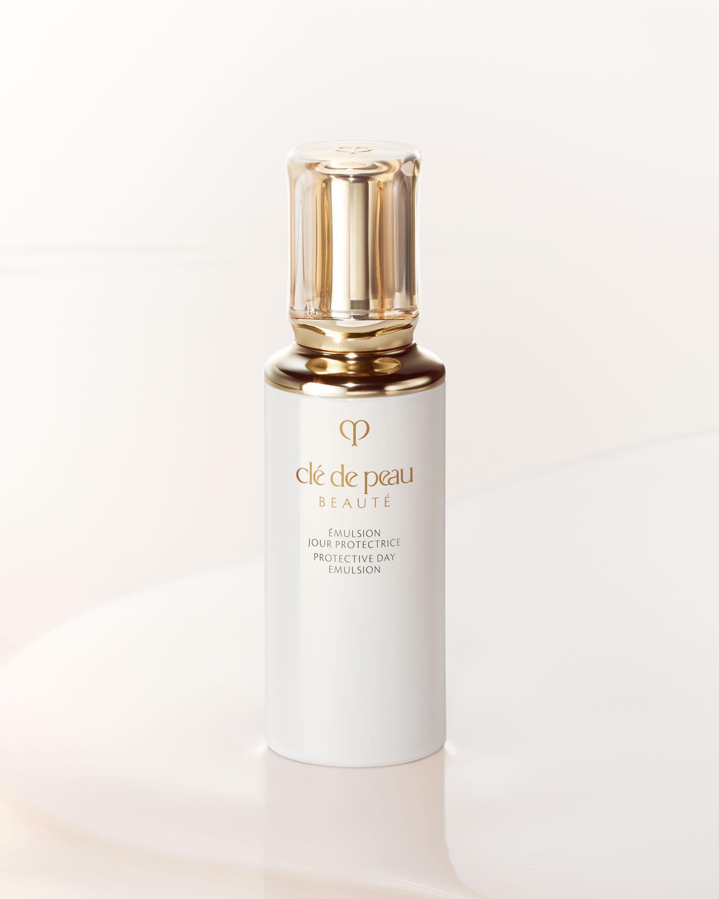 Photo of a PROTECTIVE DAY EMULSION bottle with a rounded, translucent gold cap.