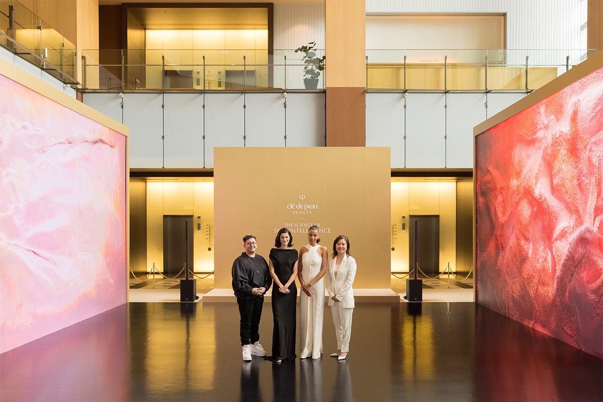 Photo of four people standing in front of a gold Clé de Peau Beauté panel.