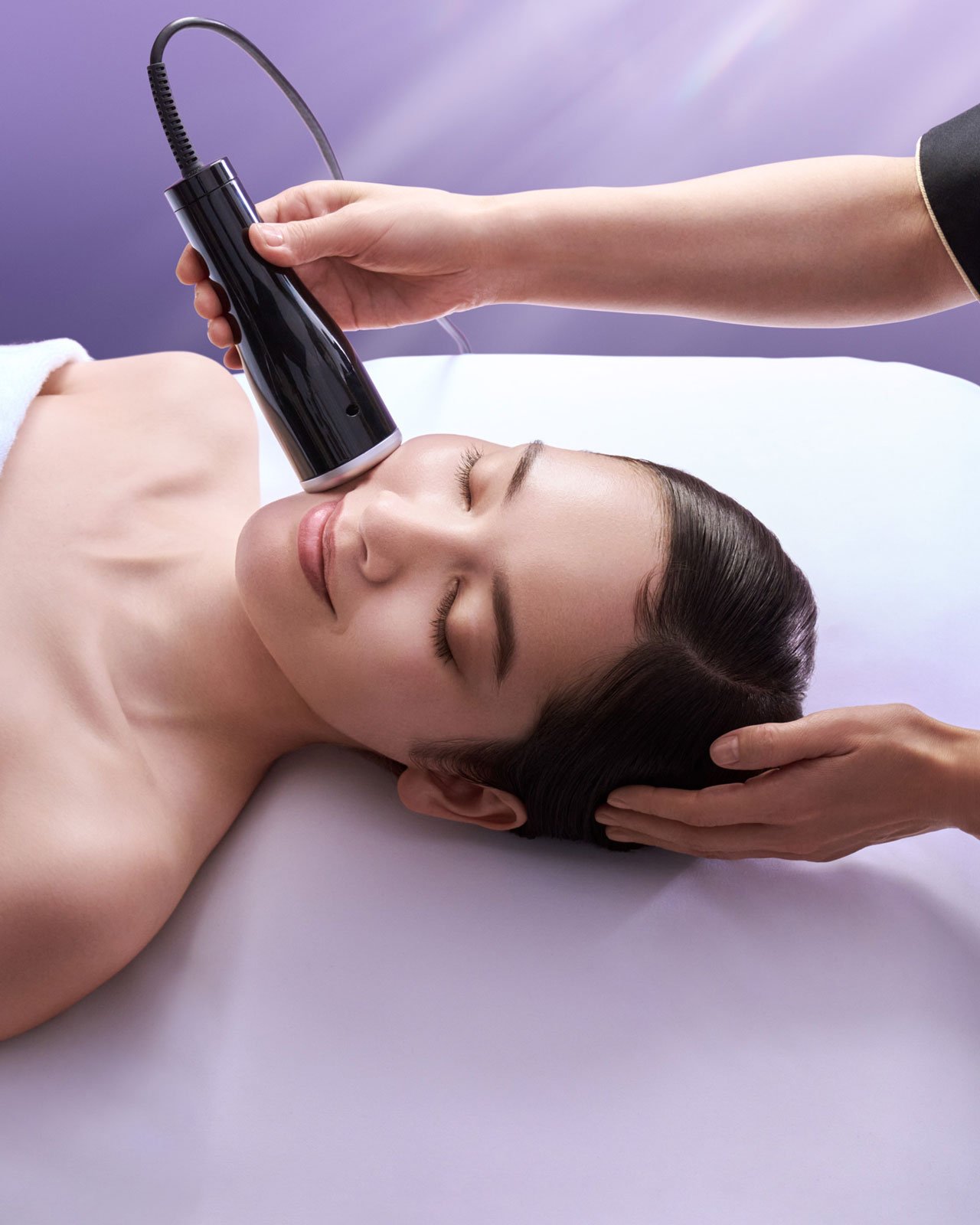 Photo of a woman receiving a treatment with a specialized device applied to her face.