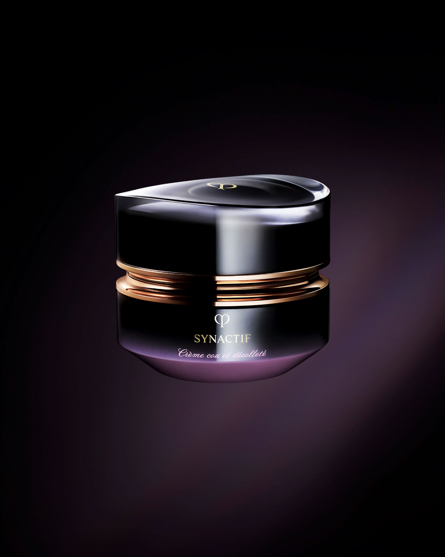 Photo of the Clé de Peau Beauté Synactif NECK & DÉCOLLETÉ CREAM. The cream is presented in a jar with a black-to-purple gradient. The lid features a sculptural gold design, and the 'SYNACTIF' logo is elegantly displayed on the front.