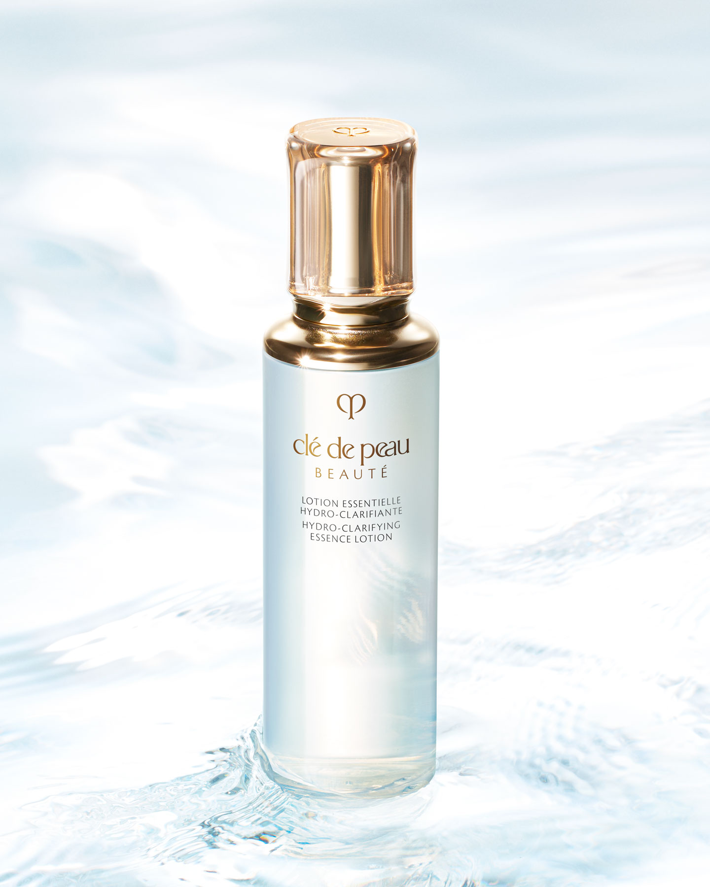 Photo of a HYDRO-CLARIFYING ESSENCE LOTION bottle with a translucent, rounded gold cap and the gold brand logo.