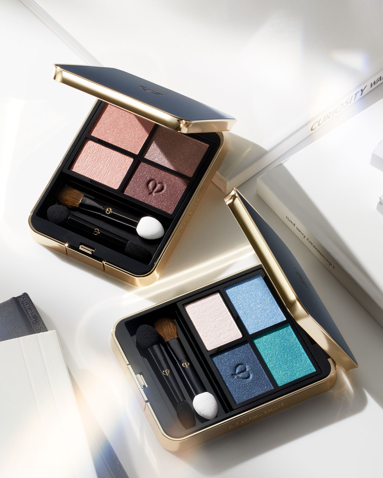 Photo of Eye Color Quad palettes No.3 and No.11 open on a table with natural light.