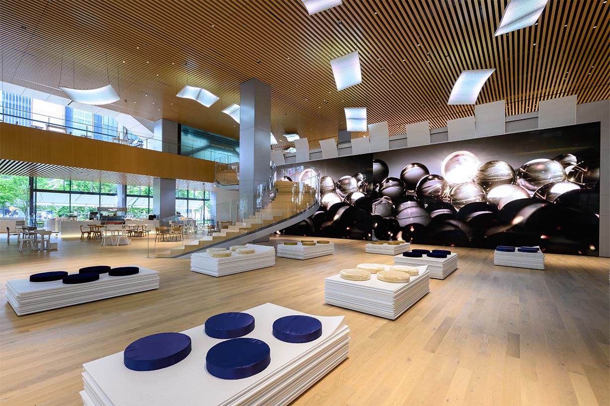 Photo of a modern lobby space featuring benches and displayed artworks.