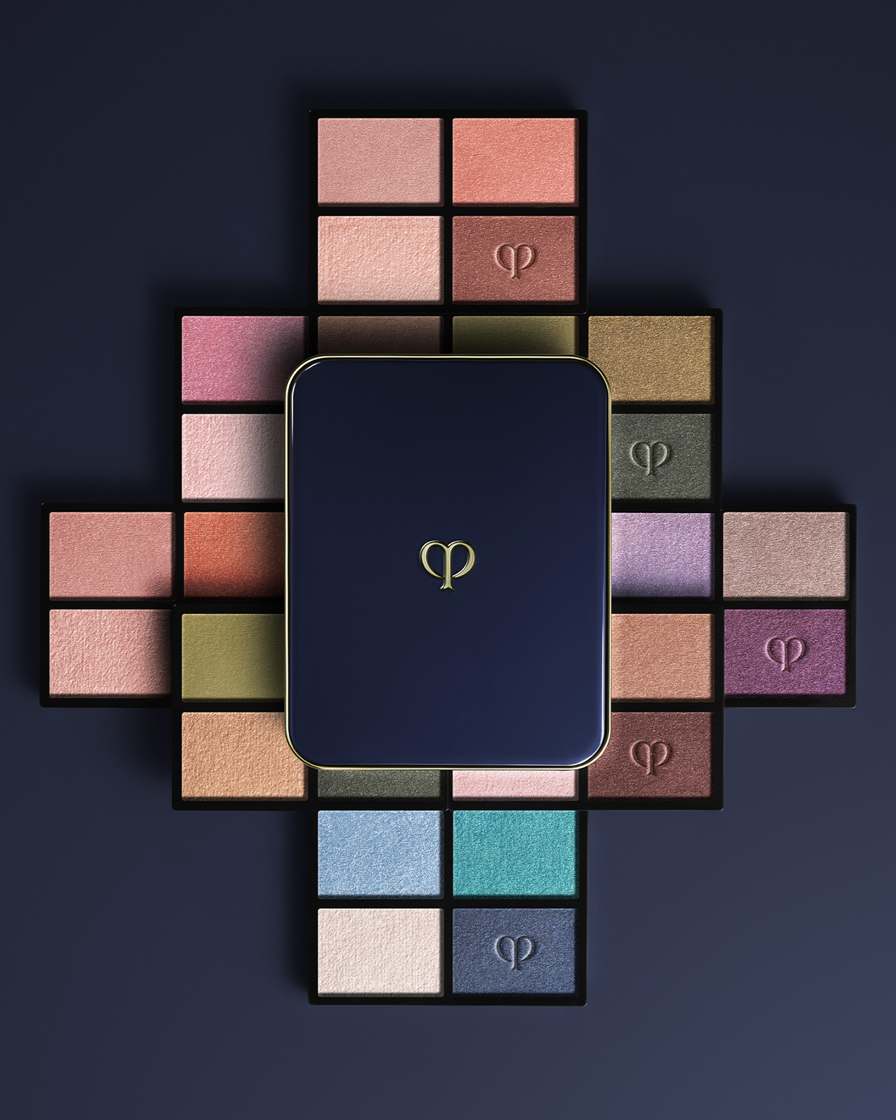 Photo of the EYE COLOR QUAD (REFILL) collection. A blue-black compact case is placed in the center, and refills in pink, blue, and beige tones are arranged in a radial pattern.