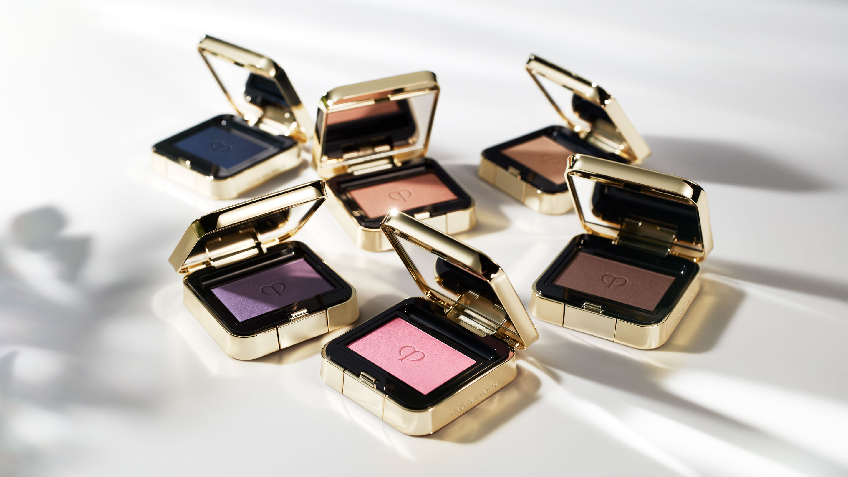 Photo of six open Eye Color Solo palettes placed at various angles on a sunlit white table.