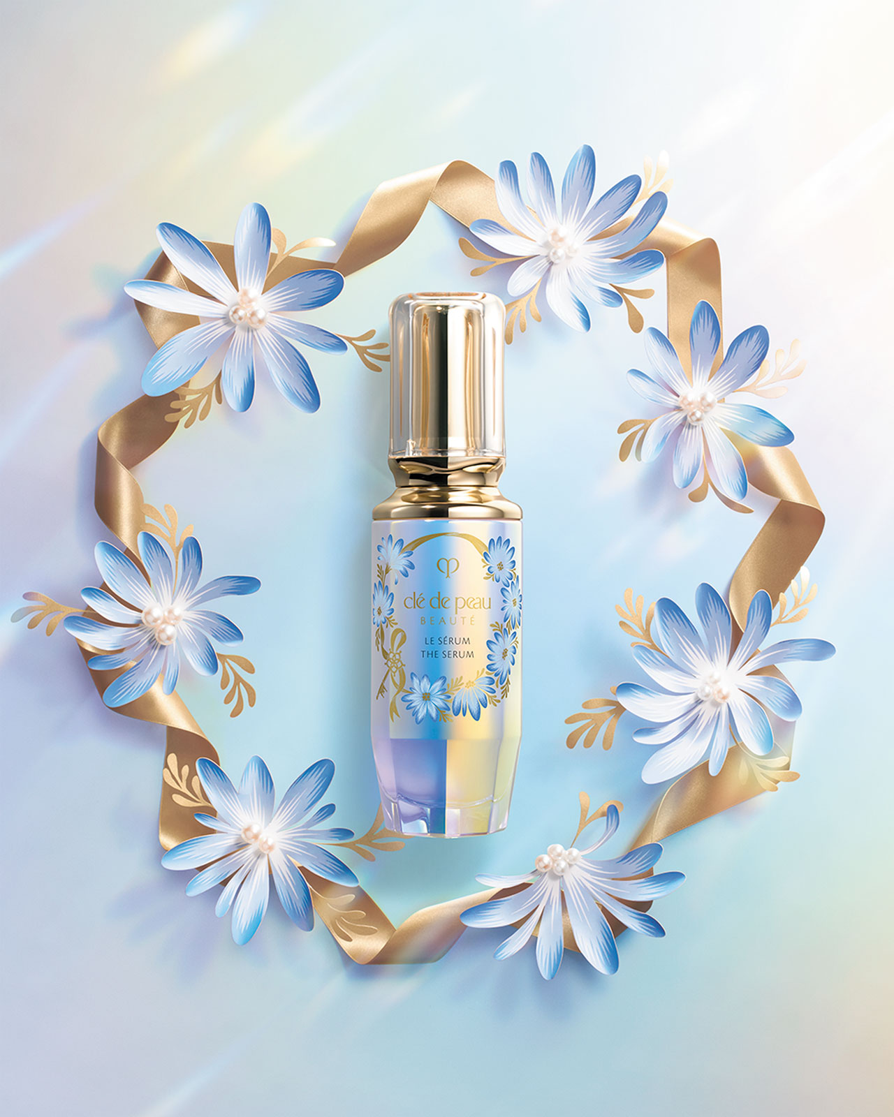Photo of Clé de Peau Beauté’s limited-edition The Serum bottle, decorated with blue floral artwork and a gold ribbon wreath.