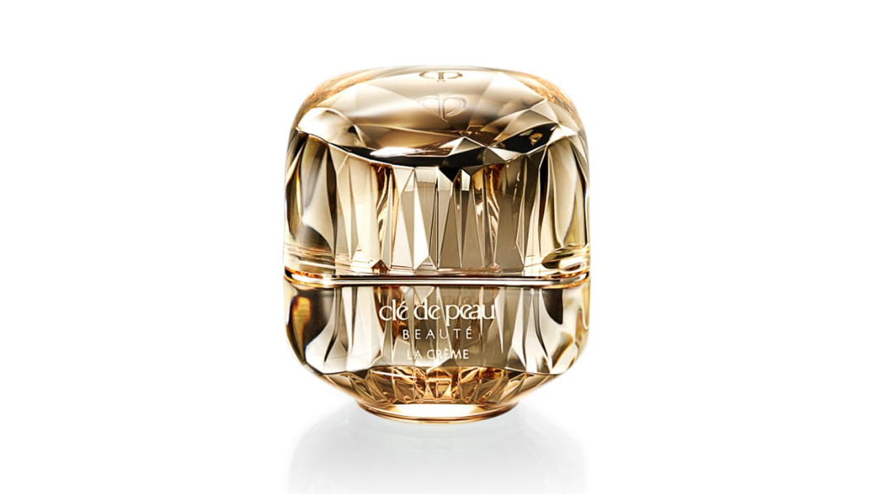 Photo of a jewel-cut, translucent gold container. The sparkling form reflects light, and the front features the brand logo and the text “LA CRÈME” (current packaging).