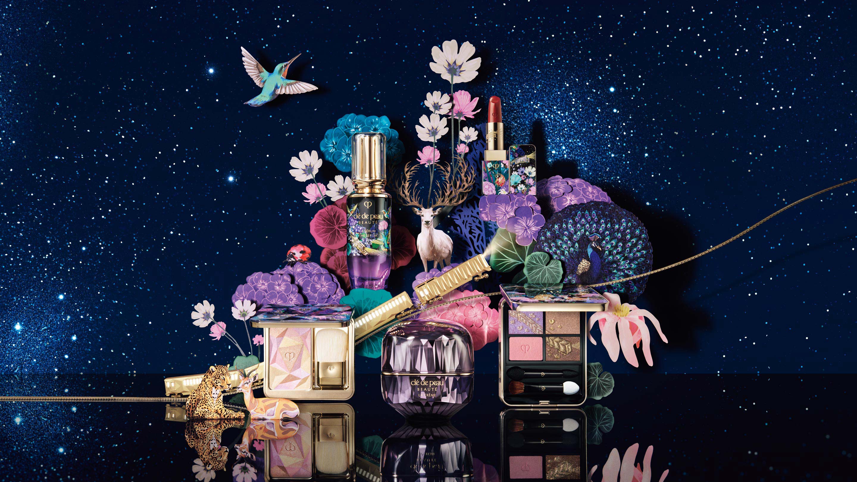 Photo of limited-edition Clé de Peau Beauté products arranged under a starry night sky, surrounded by illustrated animals such as a white deer, a peacock, and a leopard, along with colorful flowers.