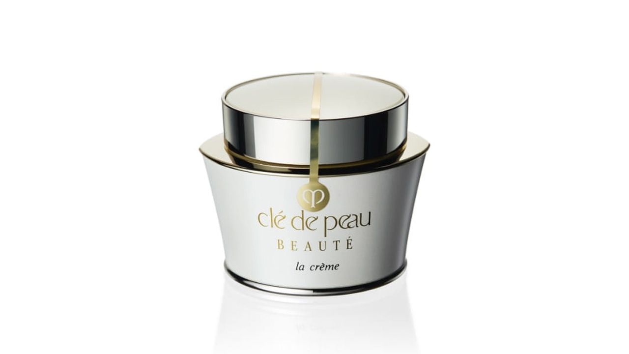 Photo of a soft white container accented with a silver cap and gold line. The front displays the brand logo and the text “la crème” (former packaging).