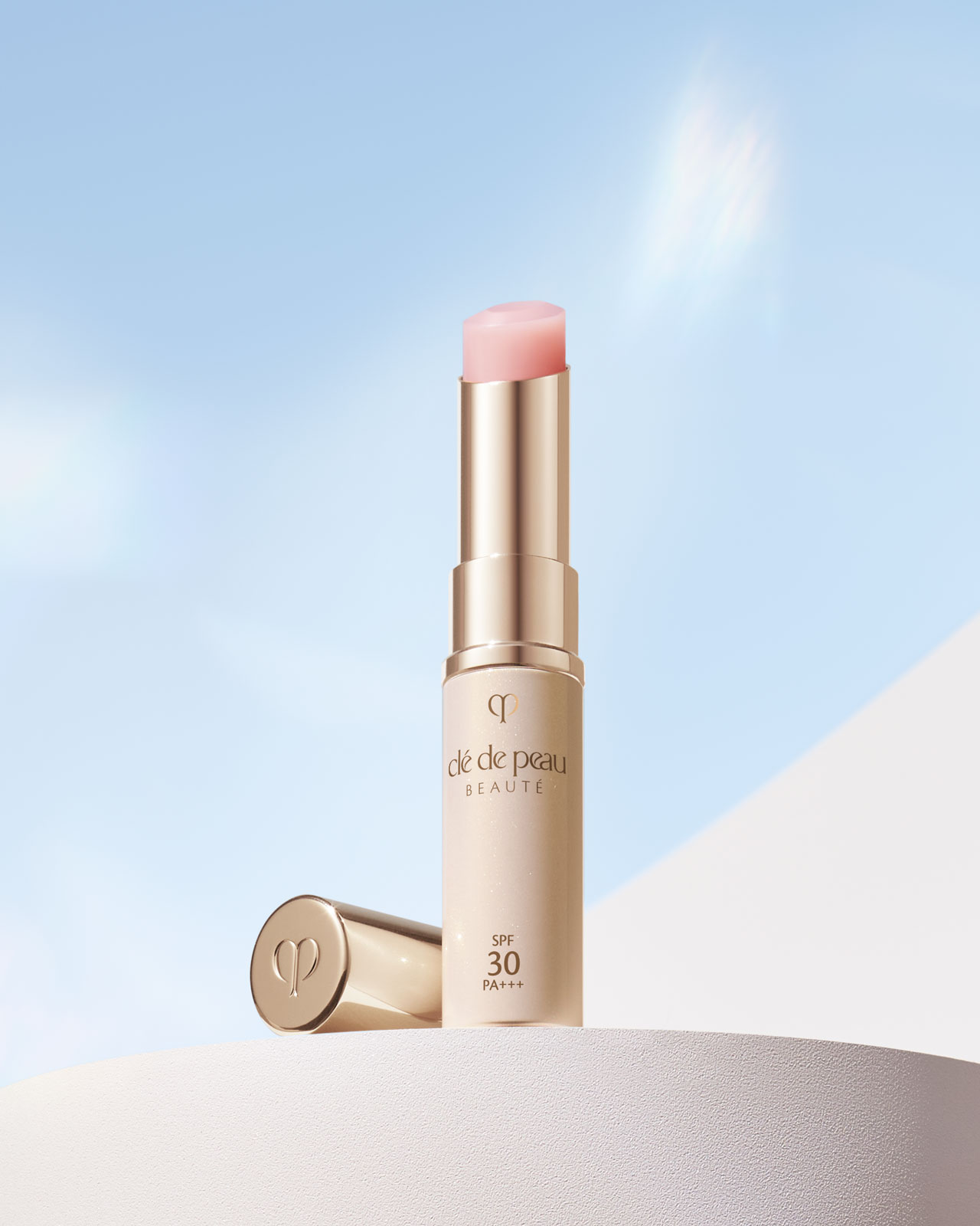 Photo of a PROTECTIVE LIP TREATMENT in a glossy, cream-colored case with a gold cap, featuring a soft pink lip color.