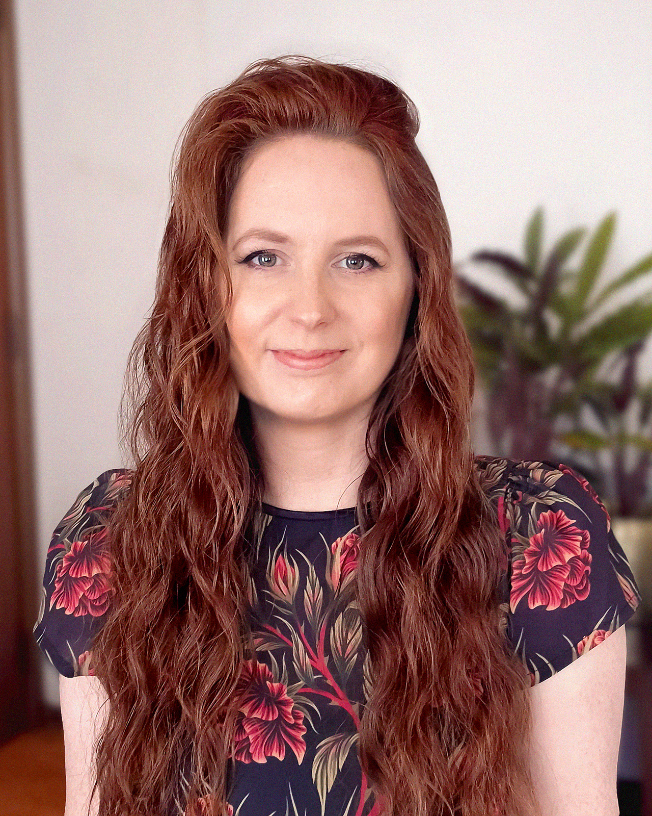 Photo of Andrea Muller, the New Zealand artist behind Clé de Peau Beauté’s 2025 gift collection, wearing a floral dress and smiling at the camera.