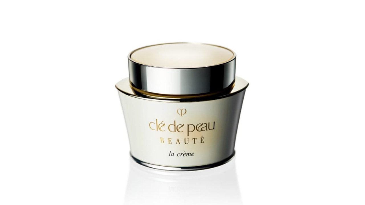 Photo of a soft beige-toned container paired with a silver cap. The front is marked with the brand logo and the text “la crème” (former packaging).