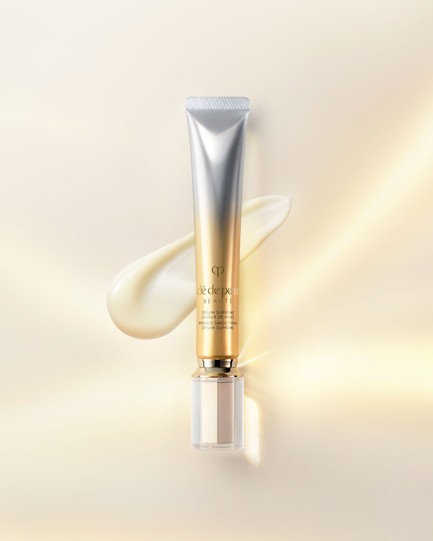 Photo of a WRINKLE SMOOTHING SERUM SUPREME tube with a clear cap and a gradient from silver at the top to gold at the bottom.