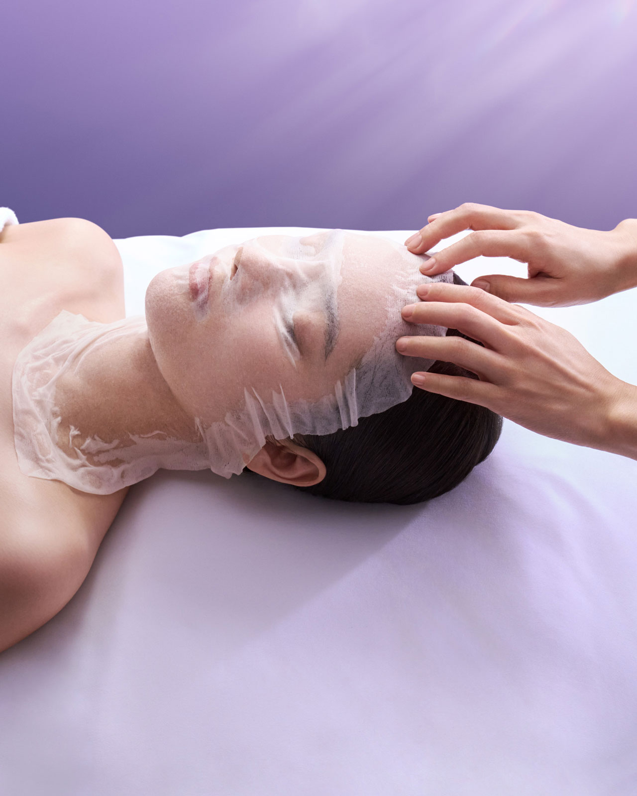 Photo of a woman wearing a lotion mask while receiving a head massage.