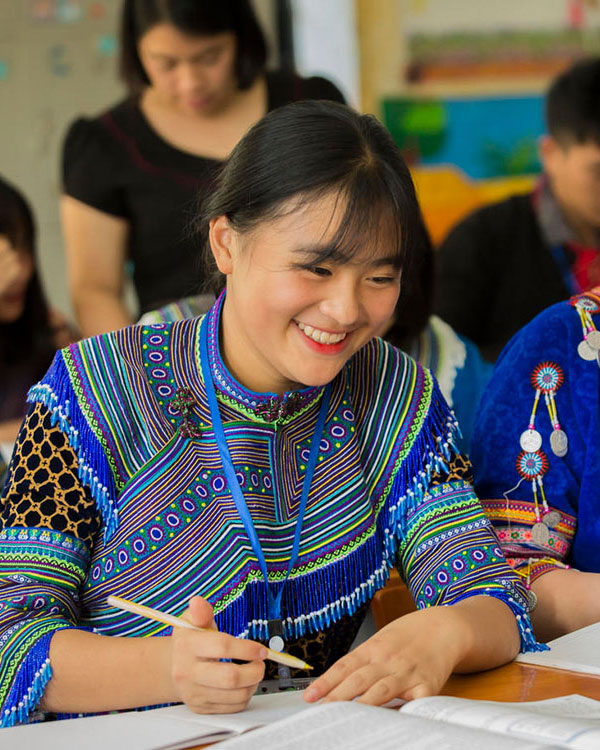 Photo of a woman in traditional attire, smiling while studying.