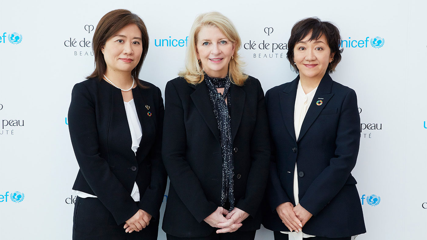 Photo of three women standing in front of a Clé de Peau Beauté and UNICEF backdrop.