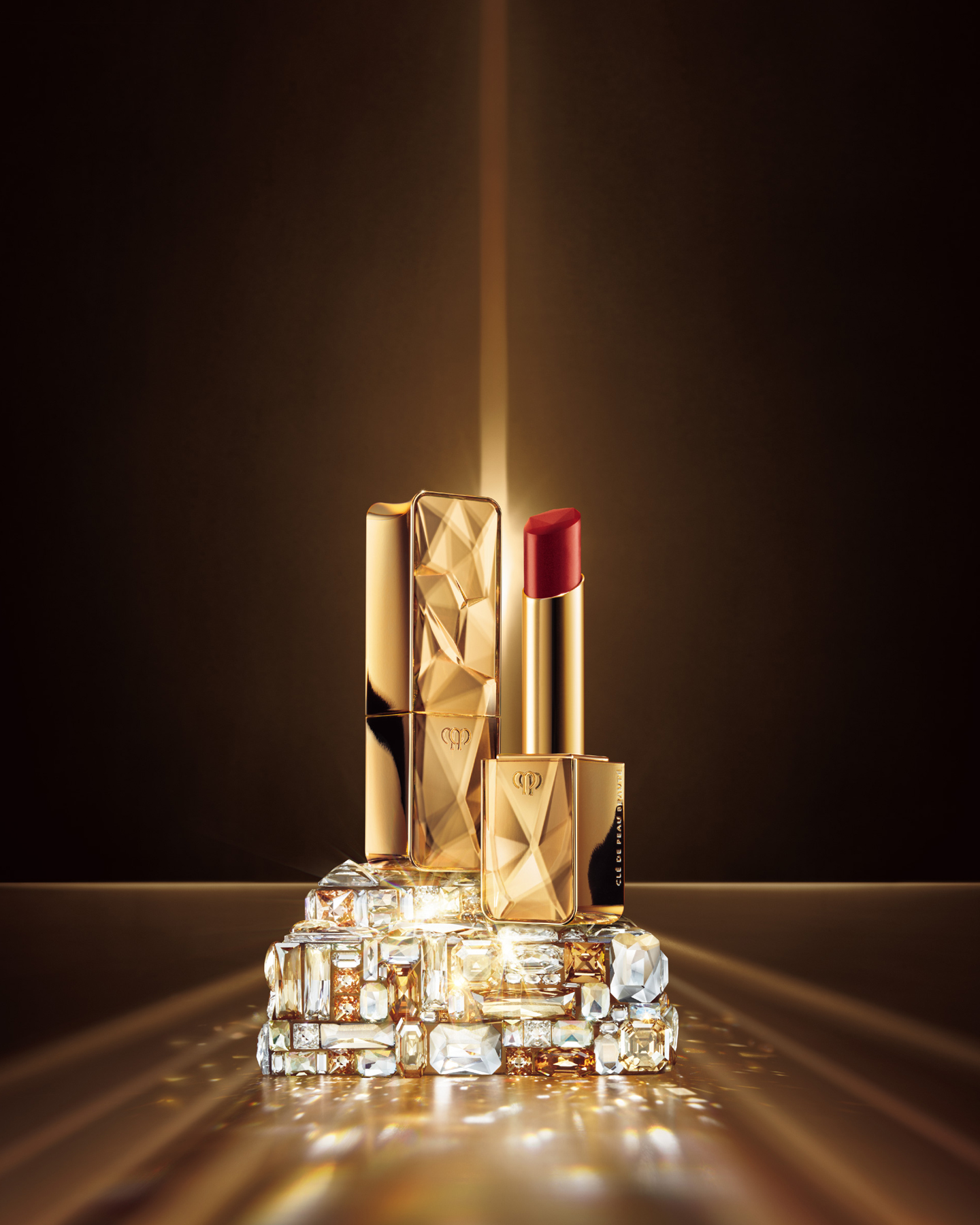Photo of THE PRECIOUS LIPSTICK, featuring a beautifully vivid red hue and a gold package with jewel-like faceting.