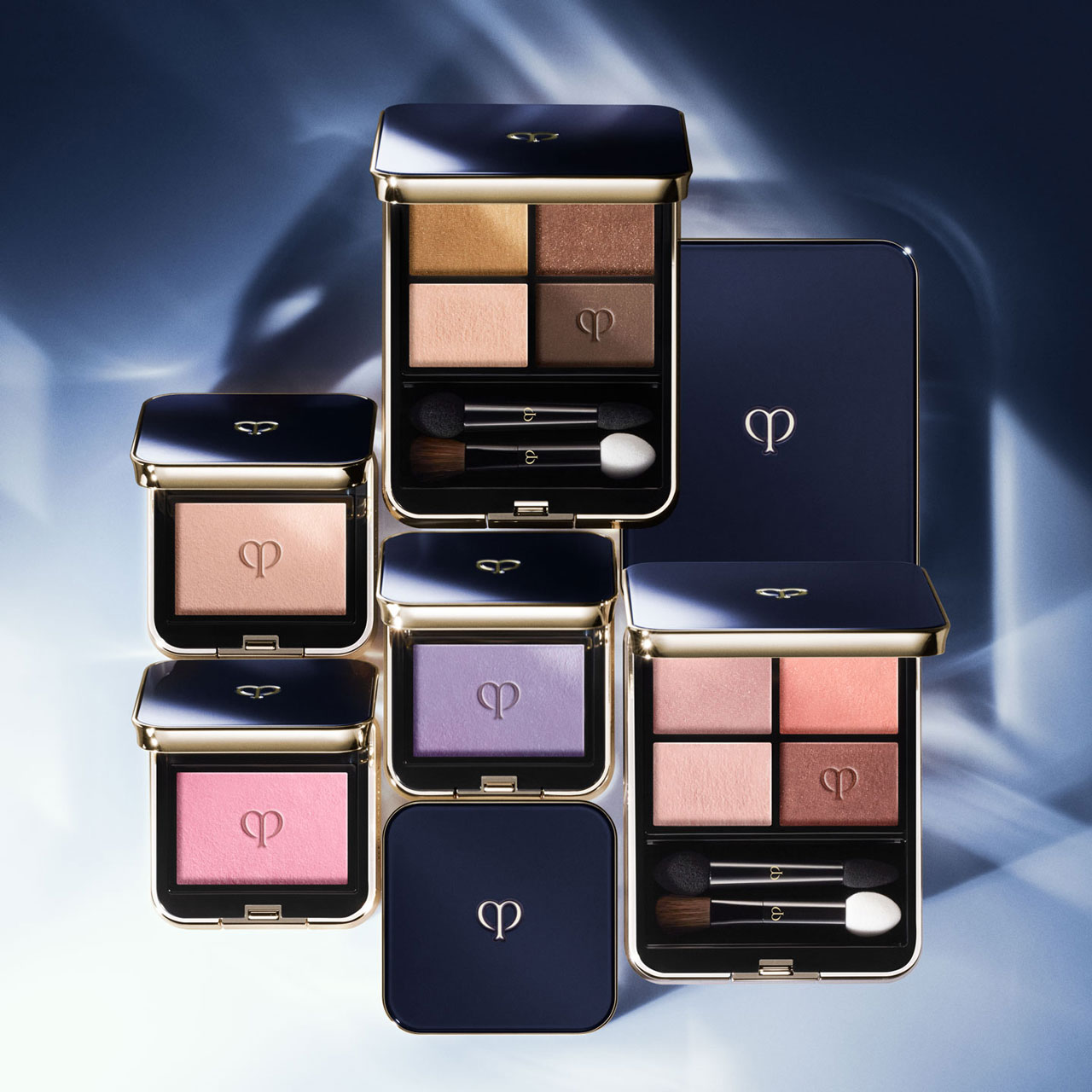 Photo of an arrangement of open and closed Eye Color Quad and Eye Color Solo palettes on a blue gradient backdrop.