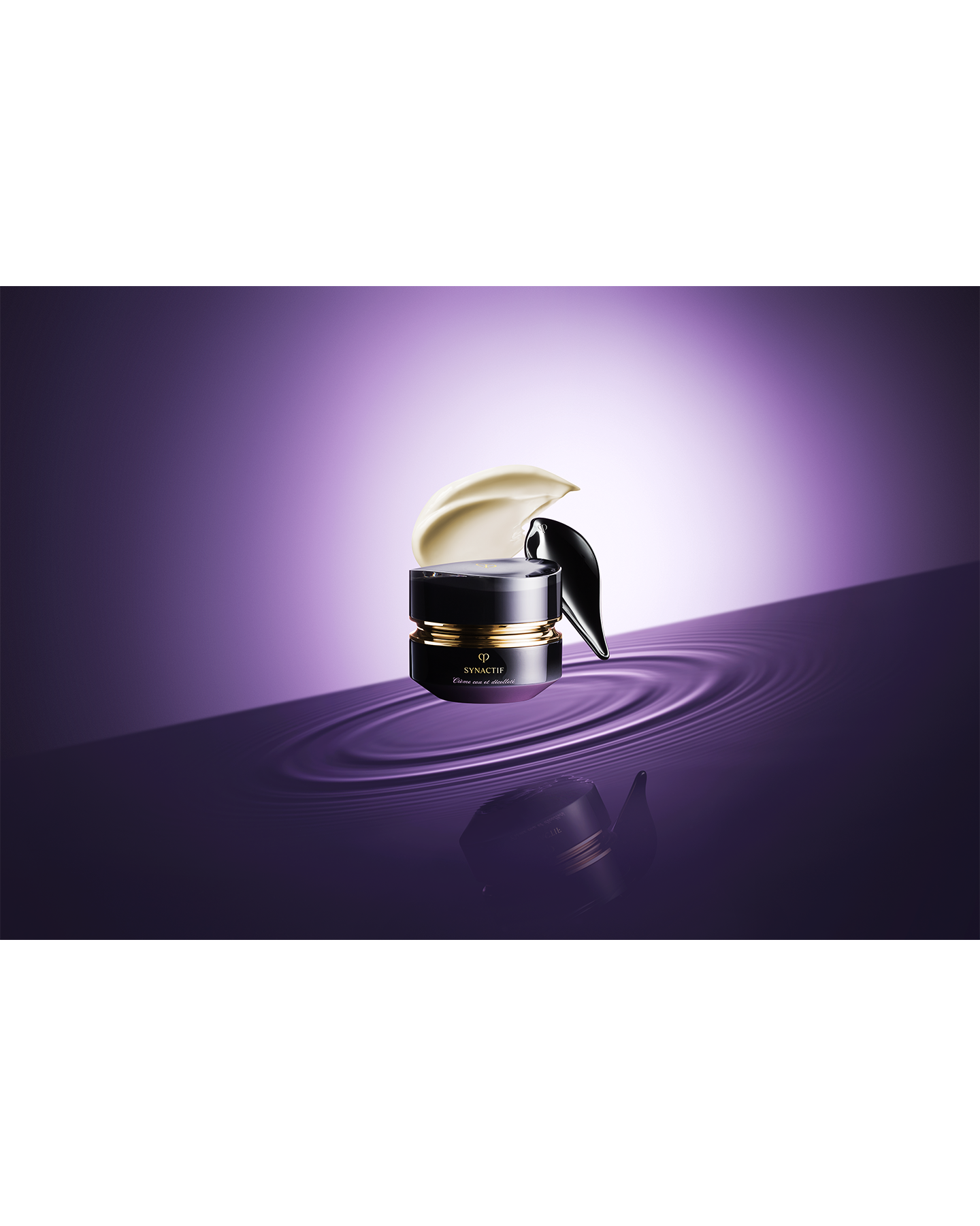 Photo of the black-themed "SYNCACTIF NECK & DÉCOLLETÉ CREAM jar is placed on a purple water surface, showcasing the creamy texture and the appearance of the cream being scooped up with a spatula.